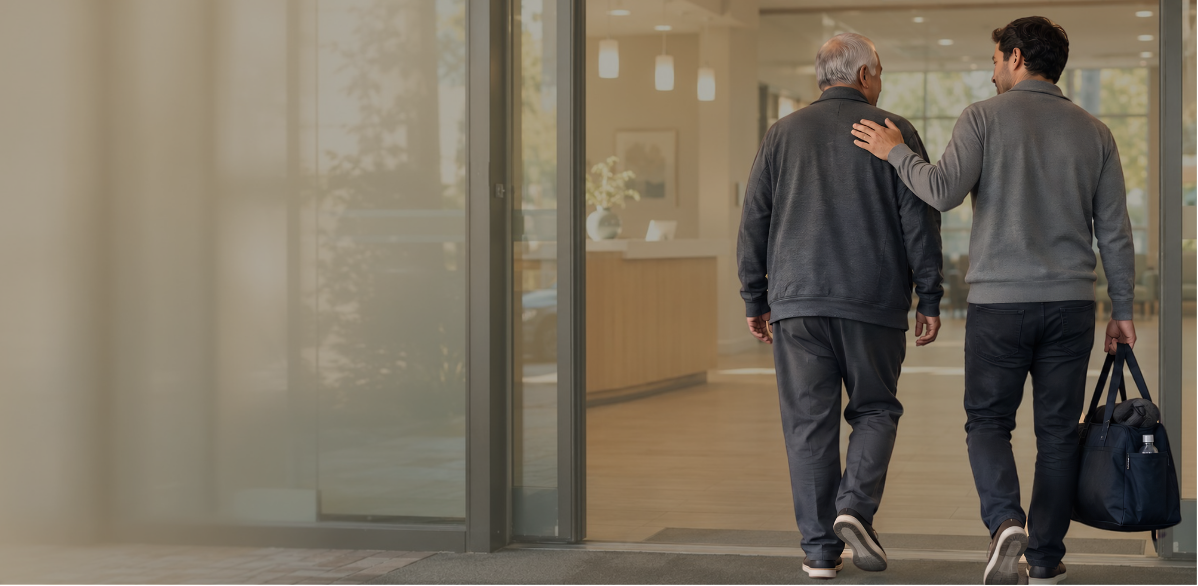 An older man and a younger family member walking together toward a dialysis center